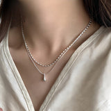 Collana a doppio strato in oro bianco con pendente a goccia